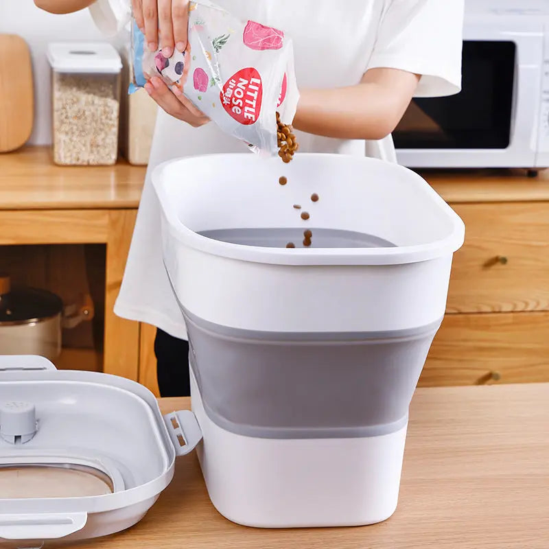 Expanded grey collapsible pet food storage bin being filled with dry kibble
